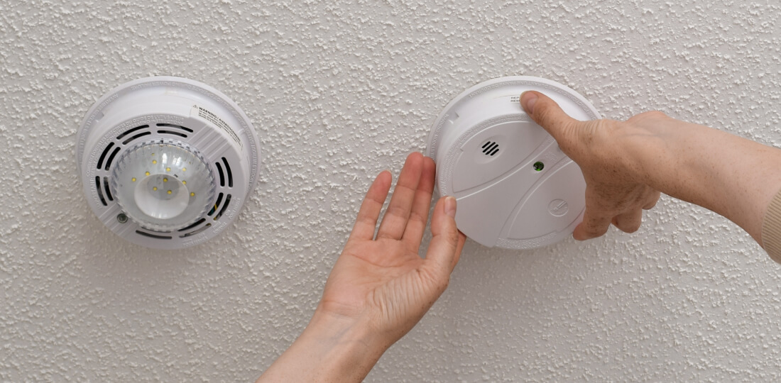 Close-up of hands checking a smoke detector