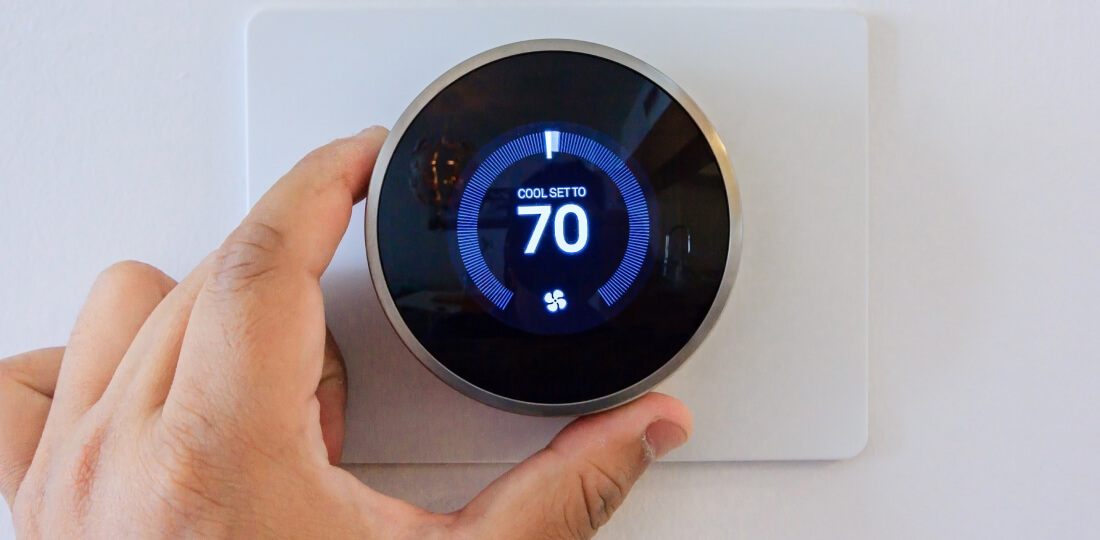 Close-up of a person's hand adjusting the thermostat